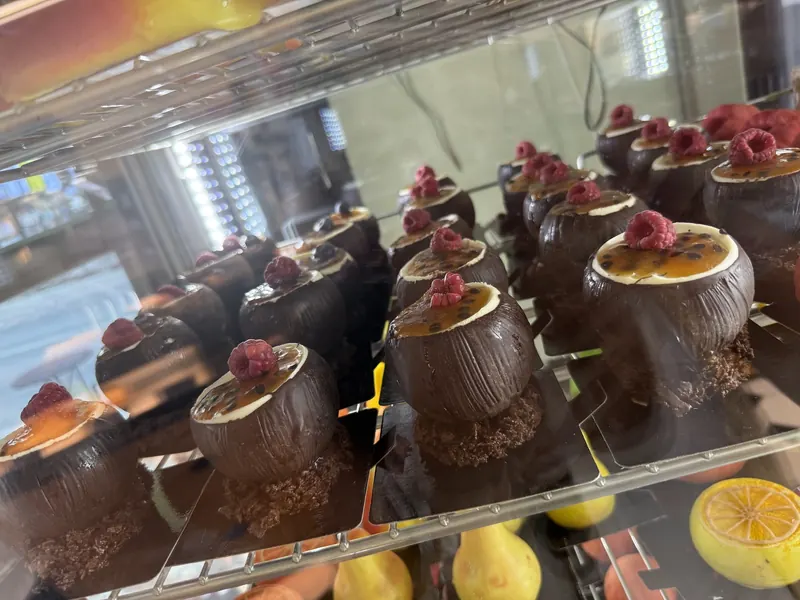 Rows of chocolate dome desserts with passion fruit and raspberries