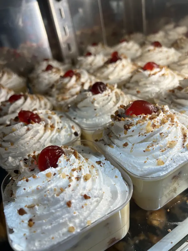 Cups of cream topped with whipped cream, crushed nuts and a cherry