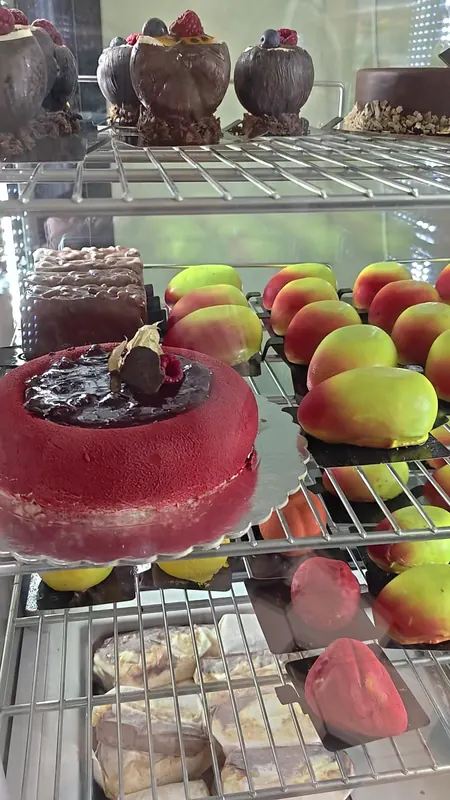 Display shelves with a red glazed cake and fruit-shaped desserts