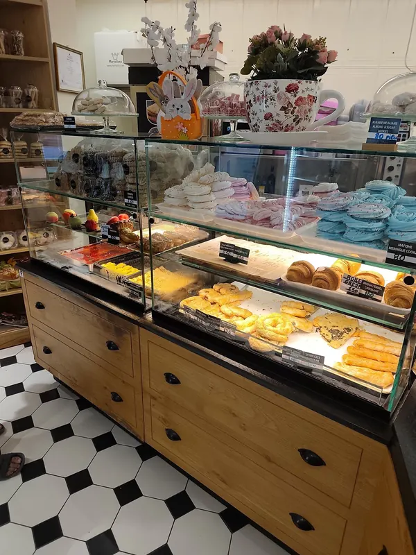Wooden pastry counter with trays of sweets and the black-and-white tiled floor